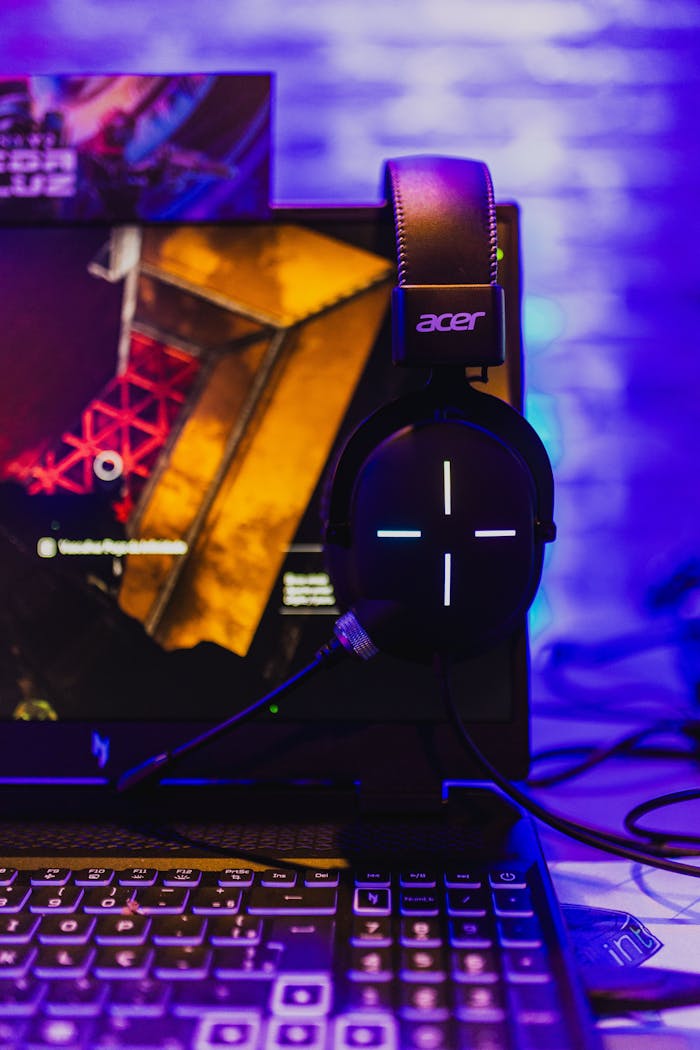 Close-up of a gaming setup featuring an Acer laptop and headset illuminated by colorful lights.